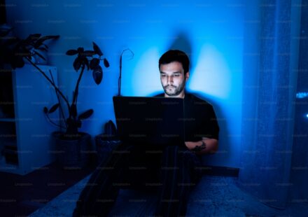 一個人在暗藍色房間裡使用筆電