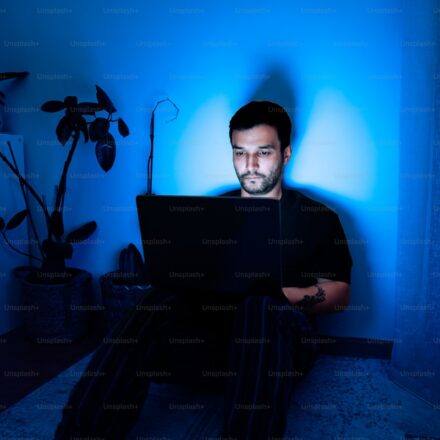 一個人在暗藍色房間裡使用筆電