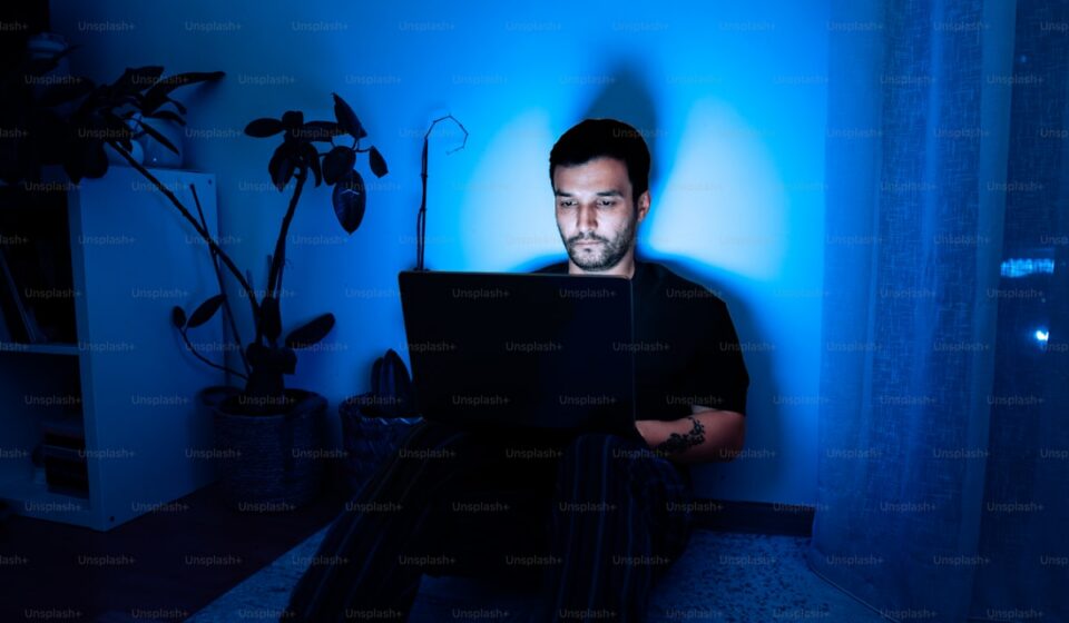 一個人在暗藍色房間裡使用筆電